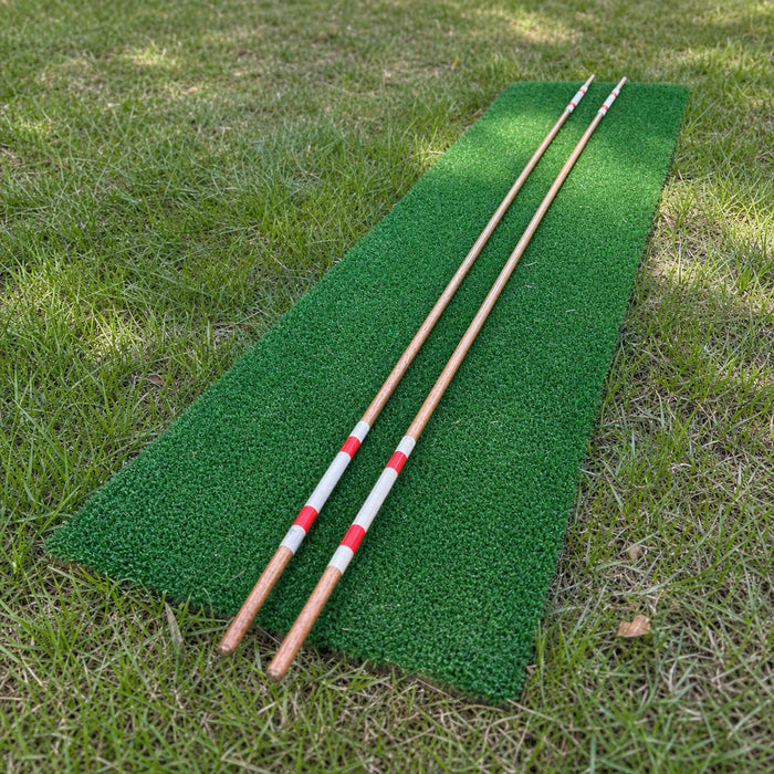 Two hand-painted hickory golf alignment sticks laid parallel on a green practice mat.