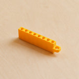 Yellow Golf Tee Holder with eight tee openings and hanging loop on pale wood