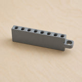 Grey Golf Tee Holder with eight tee openings and hanging loop on pale wood