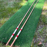 Handmade hickory golf alignment sticks, set of two, red and white bands, on a golf mat