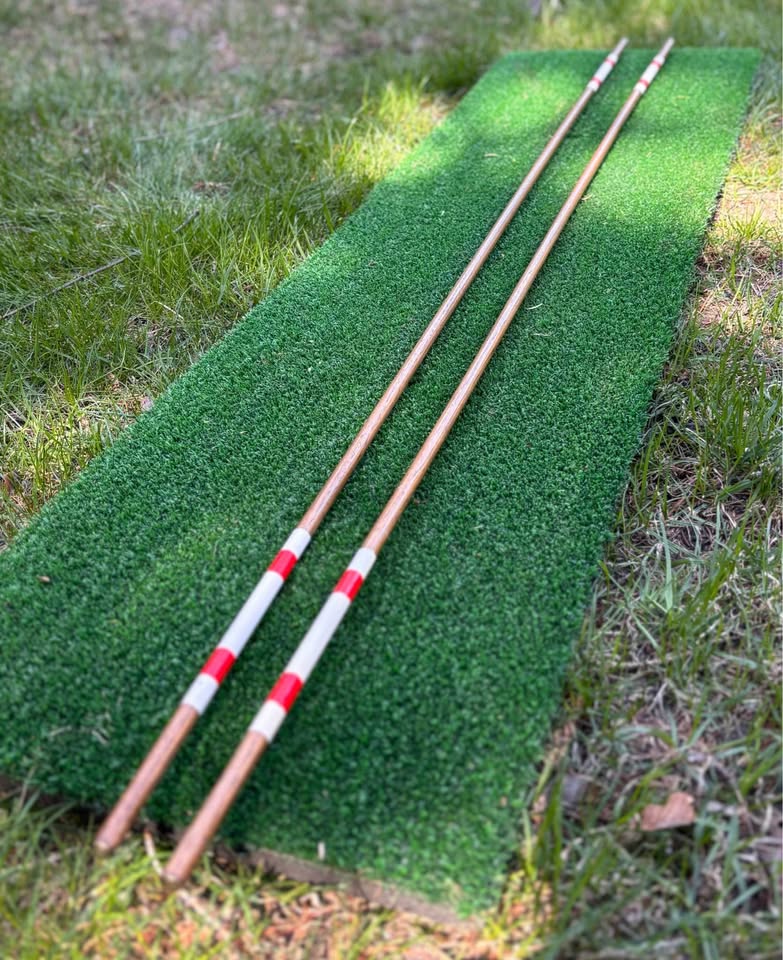 Handmade hickory golf alignment sticks, set of two, red and white bands, on a golf mat