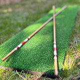 Two hickory golf alignment sticks crossed on the turf