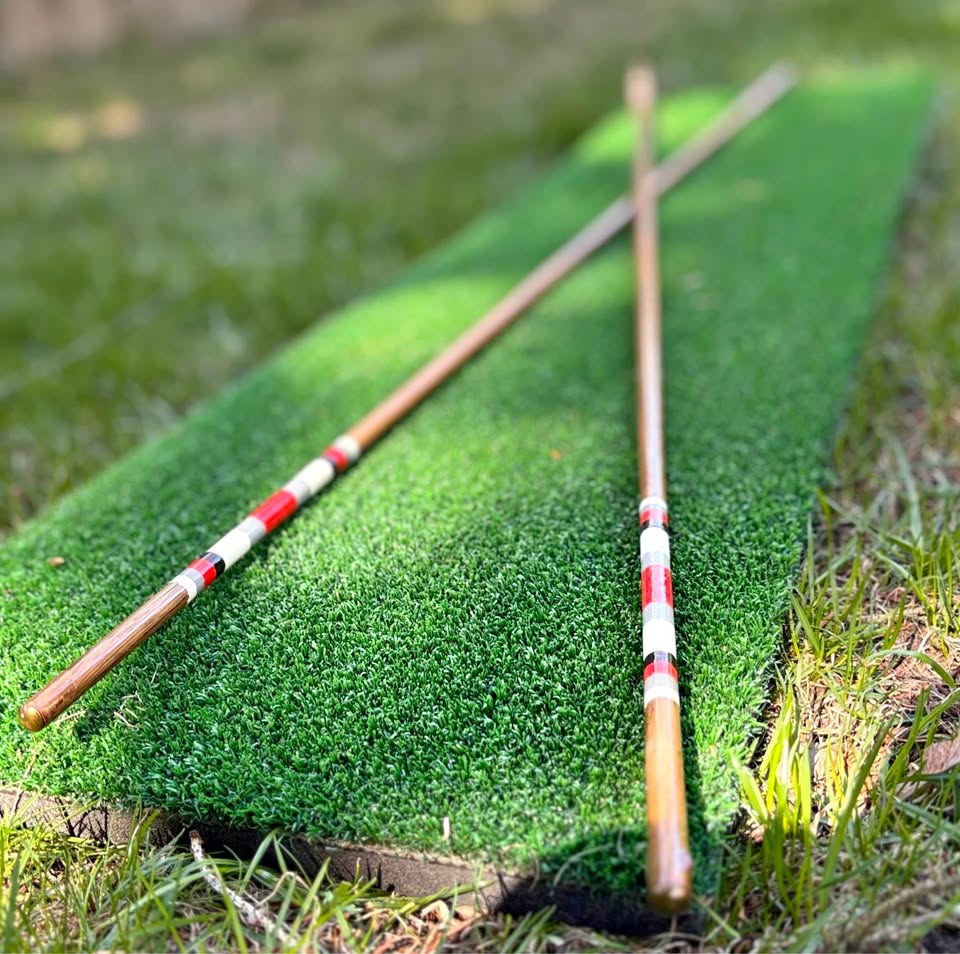 Two hickory golf alignment sticks crossed on the turf