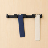 Black four-band Apple Watch band wall holder with two Apple Watch bands hanging from separate positions