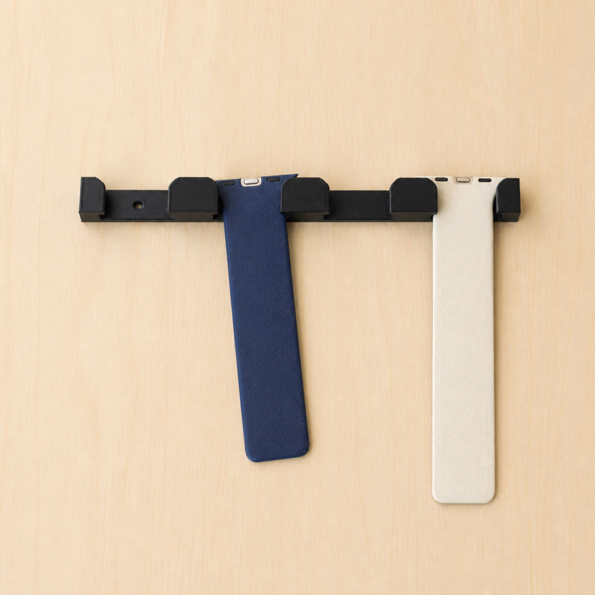 Black four-band Apple Watch band wall holder with two Apple Watch bands hanging from separate positions