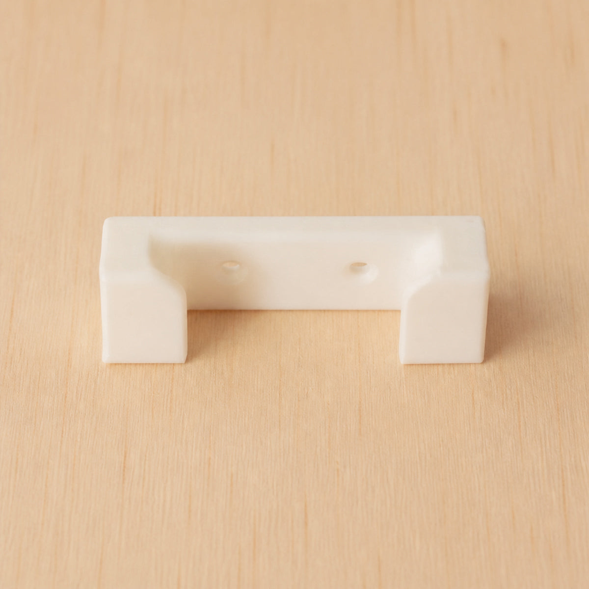 White one-band Apple Watch band wall holder shown from the front on warm plywood