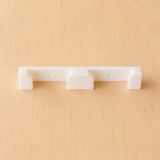 White two-band Apple Watch band wall holder shown from the front on warm plywood