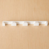White four-band Apple Watch band wall holder shown from the front on warm plywood