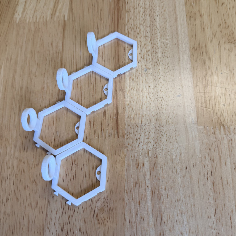 Four connected 3D printed golf ball mounts laid out on a wood bench