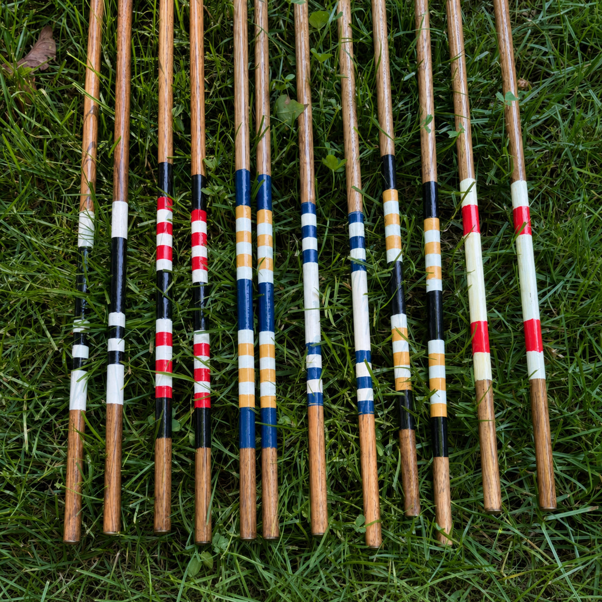 Collection of handmade hickory alignment sticks showing custom painted colour combinations