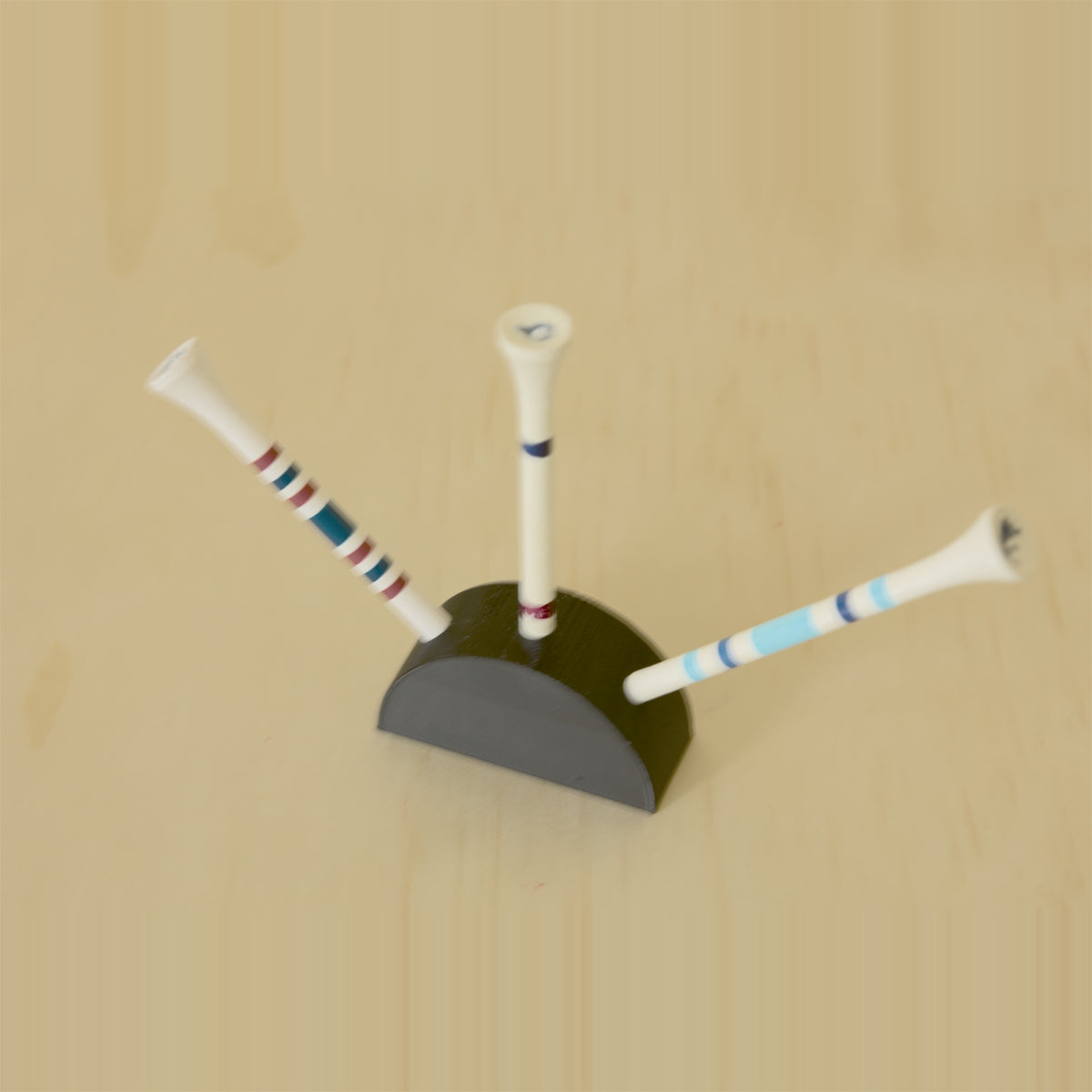 Angled view of a black curved golf tee display holding three tees