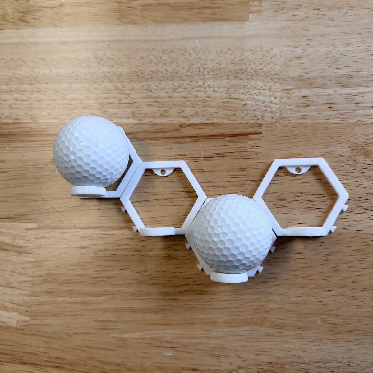 Connected white modular display mounts holding two plain white golf balls