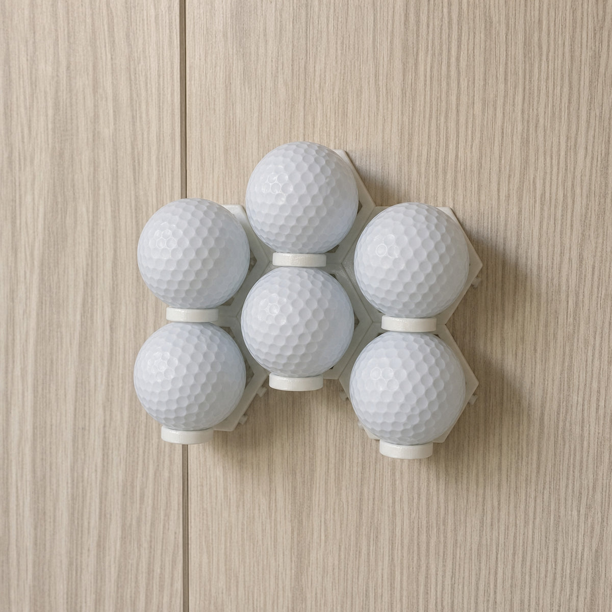 Six plain white golf balls arranged in installed modular wall display mounts