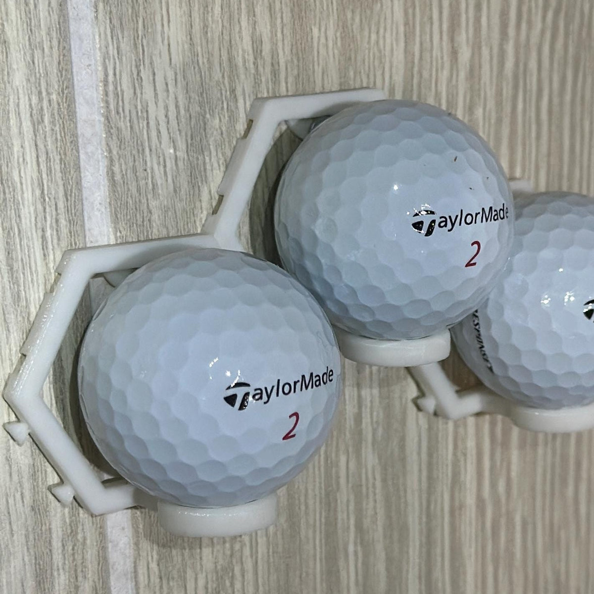 Three golf balls in the modular wall mount, side view