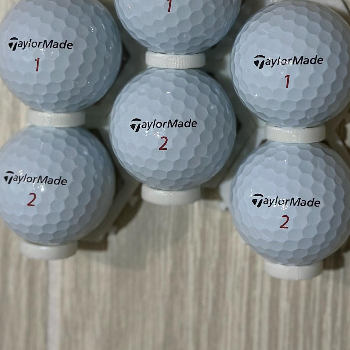 Six golf balls displayed in a pyramid of connected mounts