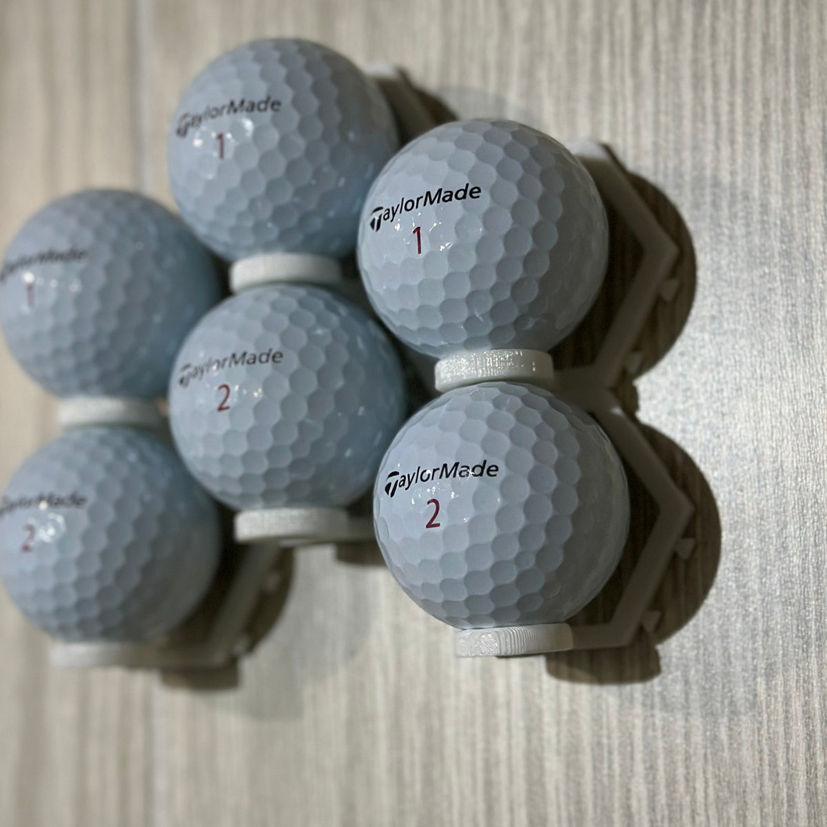 Cluster of golf balls in connected wall mounts
