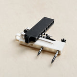 Black and white golf tee holders loaded with tees on a light wood surface
