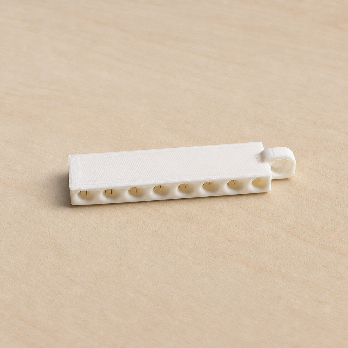 Empty white golf tee holder showing its eight tee openings and hanging loop