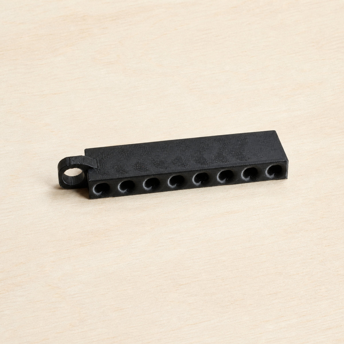 Empty black golf tee holder showing its eight tee openings and hanging loop
