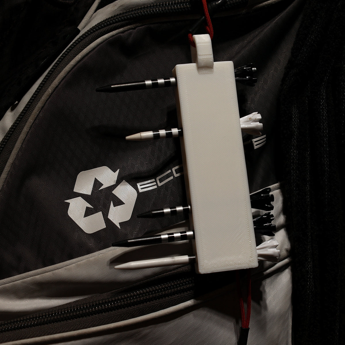 White golf tee holder loaded with tees and hanging from a golf bag