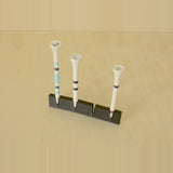 Black wall-mounted golf tee display holding three tees with one position open