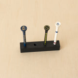 Black freestanding golf tee display holding three golf tees with one open position