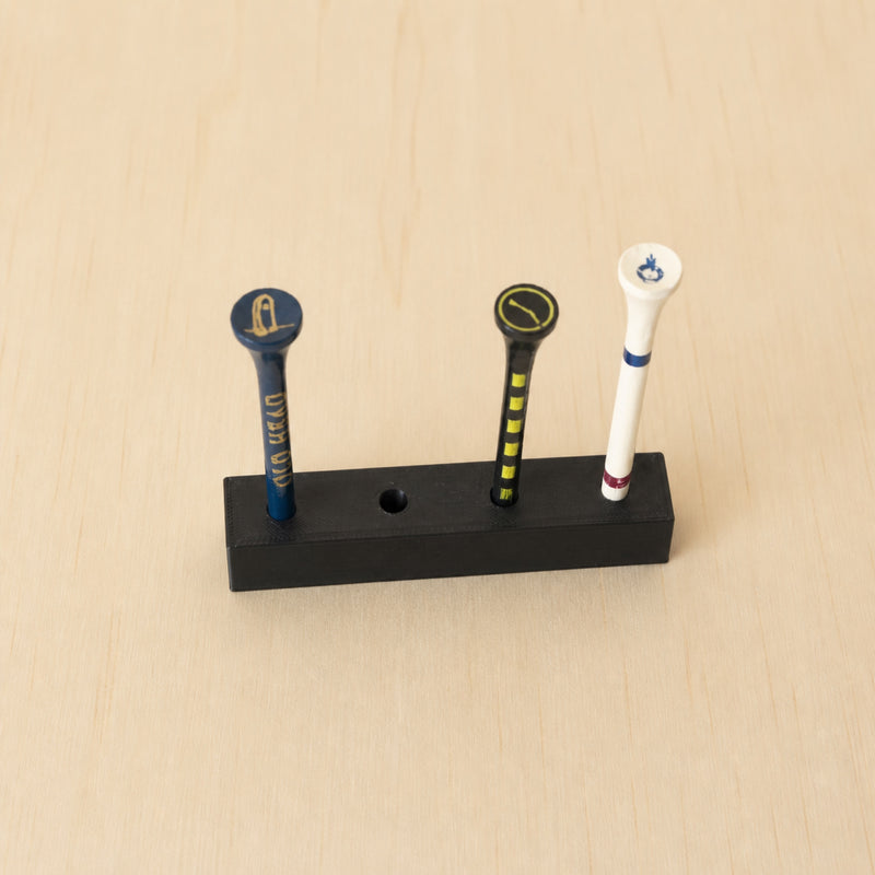 Black freestanding golf tee display holding three golf tees with one open position