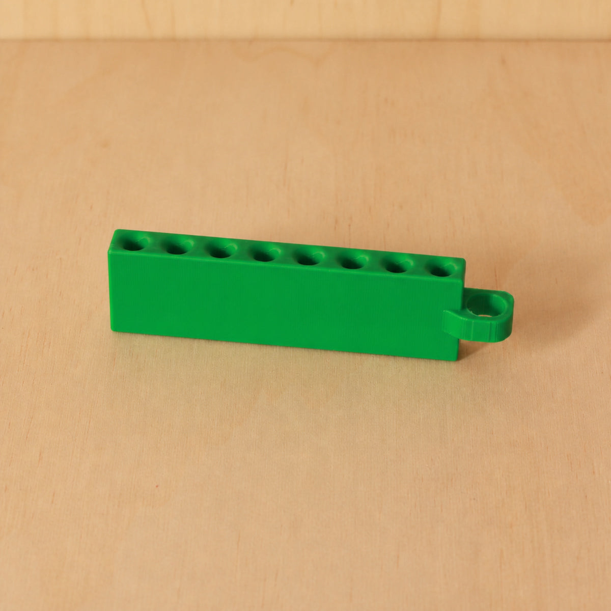 Green Golf Tee Holder with eight tee openings and hanging loop on pale wood