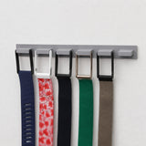 Grey wall-mounted band holder with five WHOOP bands and one empty hook